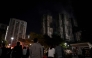 Bystanders look on after a major fire swept through several apartment blocks at the Wang Fuk Court residential estate in Hong Kong's Tai Po district on November 27, 2025. Residents anxiously awaited news of their loved ones on November 27 at a temporary shelter as one of Hong Kong's deadliest fires in decades engulfed a 2,000-unit high-rise complex. (Photo by Philip FONG / AFP)