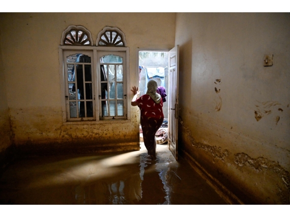 A woman inspects her damaged house after the flash floods in Meureudu, Pidie Jaya district of Indonesia's Aceh province, on November 28, 2025. (Photo by Chaideer MAHYUDDIN / AFP)
