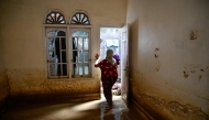 A woman inspects her damaged house after the flash floods in Meureudu, Pidie Jaya district of Indonesia's Aceh province, on November 28, 2025. (Photo by Chaideer MAHYUDDIN / AFP)

