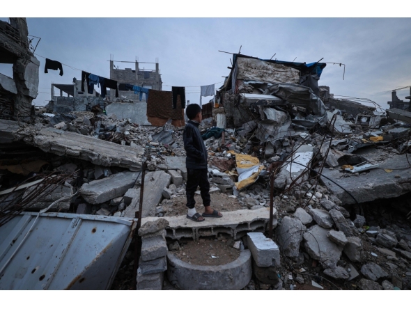 A displaced Palestinian boy stands on the ruins of destroyed buildings in the Bureij refugee camp, in the central Gaza Strip, on November 29, 2025. (Photo by Eyad Baba / AFP)