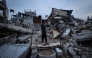 A displaced Palestinian boy stands on the ruins of destroyed buildings in the Bureij refugee camp, in the central Gaza Strip, on November 29, 2025. (Photo by Eyad Baba / AFP)