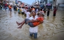 A youth carries an elderly man as they wade through a flooded street after heavy rainfall in Wellampitiya on the outskirts of Colombo on November 30, 2025. (Photo by Ishara S. KODIKARA / AFP)
