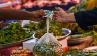 File photo: A customer buys vegetables from a stall at a market in Karachi on July 3, 2023. (Photo by Asif HASSAN / AFP)
