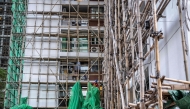 A construction worker removes the netting of bamboo scaffolding at Sui Wo Court housing estate in Fo Tan district of Hong Kong on December 4, 2025. (Photo by Philip Fong / AFP)