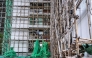 A construction worker removes the netting of bamboo scaffolding at Sui Wo Court housing estate in Fo Tan district of Hong Kong on December 4, 2025. (Photo by Philip Fong / AFP)