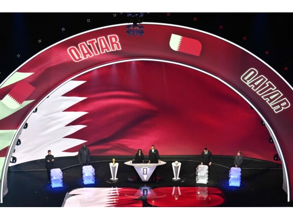 Qatar's flag is displayed on a screen during the draw for the 2026 FIFA Football World Cup taking place in the US, Canada and Mexico, at the Kennedy Center, in Washington, DC, on December 5, 2025. (Photo by Roberto SCHMIDT / AFP)