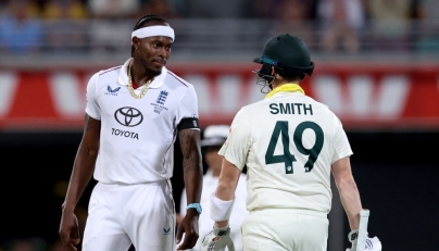 Australia's captain Steve Smith (R) reacts with England's Jofra Archer on day four of the second Ashes cricket Test match between Australia and England on December 7, 2025. (Photo by David Gray / AFP) 