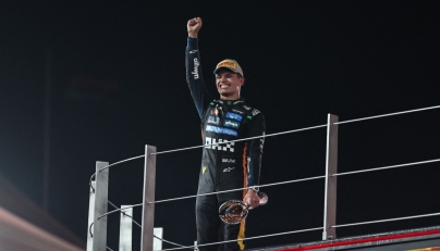 McLaren British driver Lando Norris celebrates with the trophy on the podium after finishing the race third to win the world championship title at the end of the Abu Dhabi Formula One Grand Prix at the Yas Marina Circuit in Abu Dhabi on December 7, 2025. (Photo by Fadel SENNA / AFP)