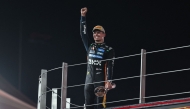 McLaren British driver Lando Norris celebrates with the trophy on the podium after finishing the race third to win the world championship title at the end of the Abu Dhabi Formula One Grand Prix at the Yas Marina Circuit in Abu Dhabi on December 7, 2025. (Photo by Fadel SENNA / AFP)