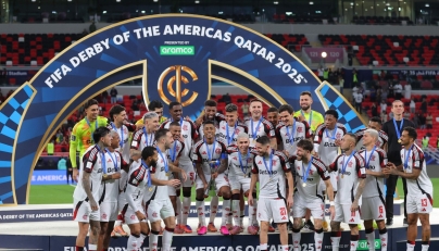 Flamengo's Bruno Henrique lifts the trophy as he celebrates with teammates after wining the FIFA Derby of the Americas match between Cruz Azul and Flamengo at Ahmad Bin Ali Stadium in Doha on December 10, 2025. (Photo by Karim JAAFAR / AFP)
