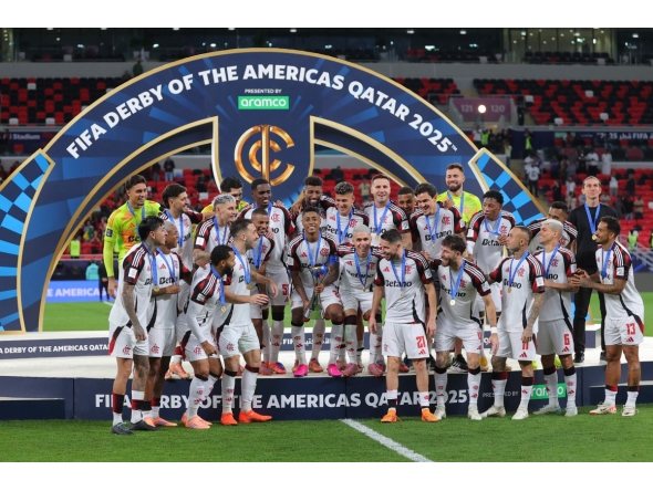 Flamengo's Bruno Henrique lifts the trophy as he celebrates with teammates after wining the FIFA Derby of the Americas match between Cruz Azul and Flamengo at Ahmad Bin Ali Stadium in Doha on December 10, 2025. (Photo by Karim JAAFAR / AFP)
