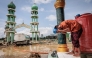 A Muslim man washes his face before attending Friday prayers at Al Ihsan Mosque, which was partially damaged by flooding, in Aceh Tamiang, North Sumatra on December 12, 2025. (Photo by Aditya Aji / AFP)
