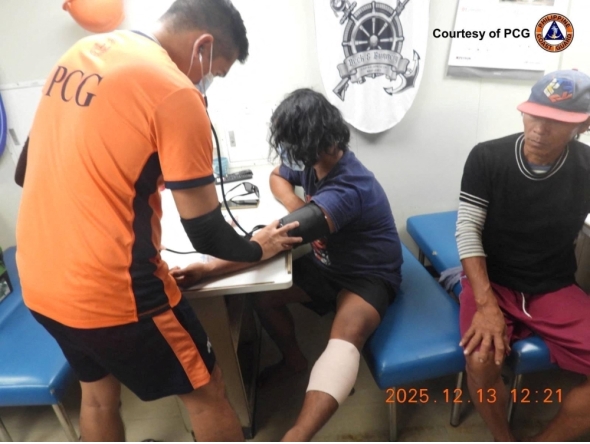 This handout photo from the Philippine Coast Guard (PCG) received on December 13, 2025, shows coast guard personnel attending to injured fishermen after an incident with China Coast Guard near Sabina Shoal in the South China Sea. (Photo by Handout / Philippine Coast Guard (PCG) / AFP) 