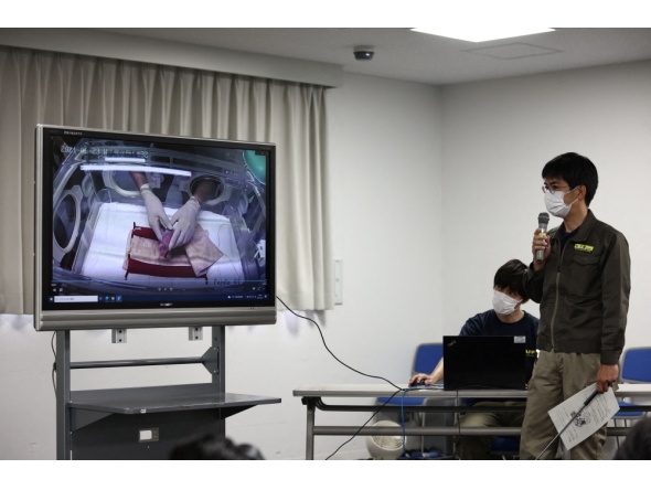 (File) Ueno Zoological Gardens staff Naoya Ohashi (R) shows an image of the first of two newly-born twin cubs delivered by giant panda Shin Shin at Tokyo's Ueno Zoo on June 23, 2021. (Photo by Behrouz Mehri / AFP)