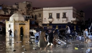 People wade through a square after a flash flood in Safi on December 14, 2025. Flash-flooding caused by sudden, heavy rain killed at least 21 people in the Moroccan coastal town of Safi on December 14, local authorities said. (Photo by AFP)