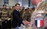 French President Emmanuel Macron shakes hands with a soldier during a Christmas diner with troops of the 5th Cuirassier Regiment's base in Zayed Military City, near Abu Dhabi, on December 21, 2025.(Photo by Ludovic MARIN / AFP)

