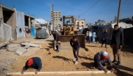 Palestinian municipality workers repair a road damaged during the war in the Nuseirat camp for the displaced in the central Gaza Strip on December 22, 2025. (Photo by Eyad Baba / AFP)