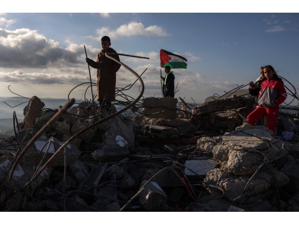 Children pose for photos taken by their parents on the rubble of a house demolished by Israeli authorities in the Palestinian village of Bizariya, in the Israeli-occupied West Bank, on December 24, 2025. (Photo by Zain JAAFAR / AFP)
