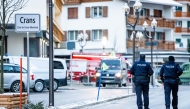 Police officers walk near ambulances at the site of an explosion that ripped through a bar in Crans-Montana on January 1, 2026.  (Photo by Maxime Schmid / AFP)