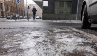 Melting ice is seen on the ground as a commuter makes his way in central Berlin, on January 13, 2026. Photo by Amelie HEIDUK / AFP