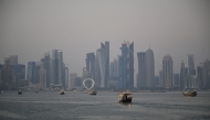 Tourists ride traditional boats along the corniche promenade in Doha on January 13, 2026. (Photo by Mahmud HAMS / AFP)
