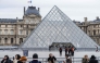 Tourists stand behind barriers blocking the access to the Louvre main courtyard, La Cour Napoleon, with the Louvre Pyramid, designed by Chinese-US architect Ieoh Ming Pei, as the Louvre Museum is closed due a strike, in Paris, on January 12, 2026. Photo by Martin LELIEVRE / AFP