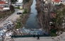 (Files) Local residents walk on a bridge, above plastic trash-filled floodwaters following heavy rains, in Durres, on January 13, 2026. (Photo by Adnan Beci / AFP)