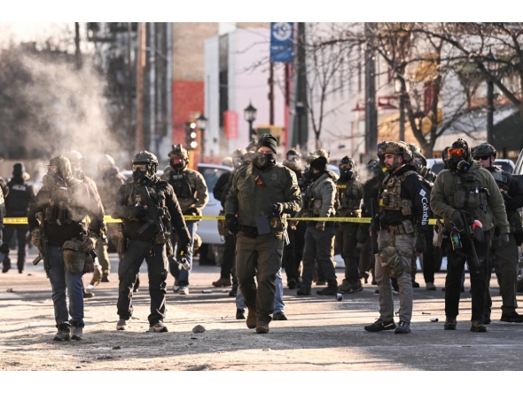 Federal agents stand near police tape as demonstators gather near the site of where state and local authorities say a man was shot by federal agents earlier in the morning in Minneapolis, Minnesota, on January 24, 2026. (Photo by ROBERTO SCHMIDT / AFP)