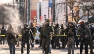 Federal agents stand near police tape as demonstators gather near the site of where state and local authorities say a man was shot by federal agents earlier in the morning in Minneapolis, Minnesota, on January 24, 2026. (Photo by ROBERTO SCHMIDT / AFP)
