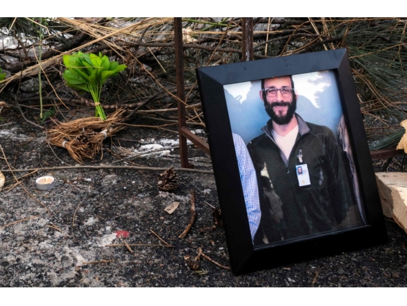 A photograph of 37-year-old Alex Pretti can be seen at a makeshift memorial in the area where he was shot dead by federal immigration agents earlier in the day in Minneapolis, Minnesota, on January 24, 2026. (Photo by Roberto Schmidt / AFP)