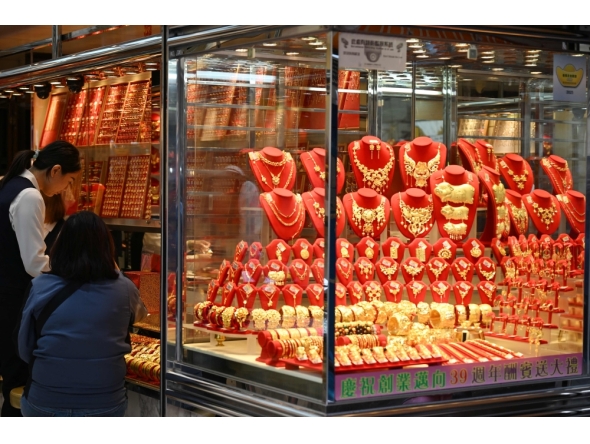 A customer (2nd L) visits a shop selling gold in Hong Kong on January 26, 2026. (Photo by Peter Parks / AFP)