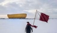 Photo shows a penguin in front of Lusail Stadium holding the Qatari flag, taken from a social media post by the Qatar Football Association.