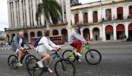 Tourists ride bicycles along a street in Havana on February 2, 2026. (Photo by YAMIL LAGE / AFP)