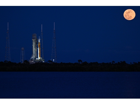 A full moon rises as the Space Launch System (SLS) rocket and the Orion spacecraft, integrated for the Artemis II mission, are seen at the Kennedy Space Center, on February 1, 2026. (Photo by Miguel J. Rodriguez Carrillo / AFP)
 