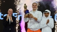 Karolina Muchova celebrates with the winner's trophy. QTSBF President Nasser Al Khelaifi and FIFA President Gianni Infantino are also present.