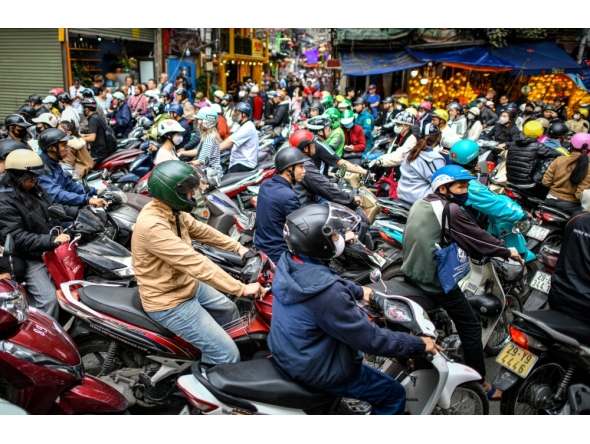 Motorists cross railway tracks on the motorbikes after a train passed on the popular train street in Hanoi on February 13, 2026. (Photo by Amaury Paul / AFP)
