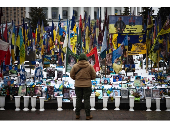 A person stands at a makeshift memorial to fallen Ukrainian and foreign soldiers in Independence Square in Kyiv on February 23, 2026. (Photo by HENRY NICHOLLS / AFP)