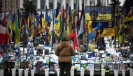 A person stands at a makeshift memorial to fallen Ukrainian and foreign soldiers in Independence Square in Kyiv on February 23, 2026. (Photo by HENRY NICHOLLS / AFP)