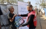 A QRCS representative hands over food aid to displaced people in Gaza. 
