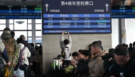 A man takes pictures of a board with a sign for the K27 train bound for Pyongyang as passengers wait for their train at Beijing Railway Station in Beijing on March 12, 2026. The first passenger train service from North Korea to China crossed the border March 12 for the first time in six years, Yonhap News Agency reported. (Photo by Adel Berry/ AFP)
 