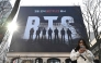 A woman uses her smartphone in front of a billboard promoting a comeback concert of K-pop boy group BTS at Gwanghwamun Square in Seoul on March 17, 2026. (Photo by Jung Yeon-je / AFP)
 