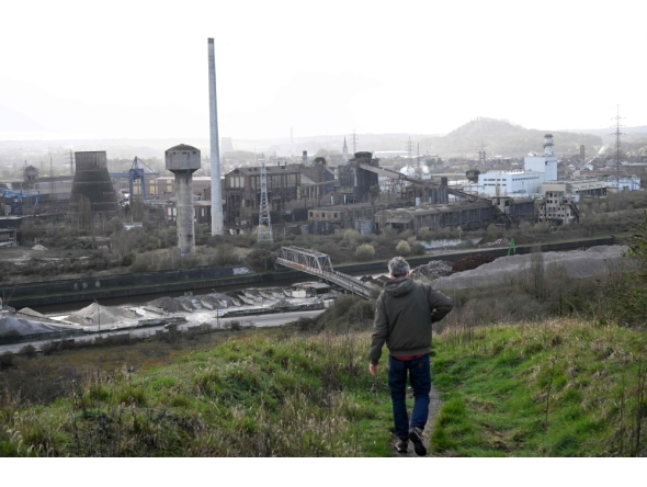 A tourist walks down a slag heap next to abandoned steel plants in Charleroi, southern Belgium, on March 11, 2026. (Photo by Nicolas Tucat / AFP)