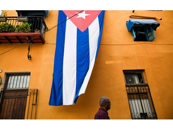 A man walks past a Cuban flag hanged on the facade of a house in Havana on March 26, 2026. (Photo by Yamil Lage / AFP)