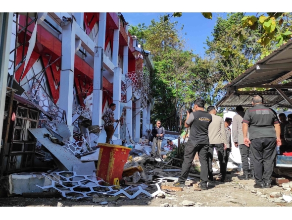 Police officers look at a building of the North Sumatra's National Sports Committee of Indonesia (KONI) damaged following a severe 7.4-magnitude offshore quake in Manado, North Sulawesi on April 2, 2026. (Photo by Tonny Rarung / AFP)