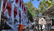 Police officers look at a building of the North Sumatra's National Sports Committee of Indonesia (KONI) damaged following a severe 7.4-magnitude offshore quake in Manado, North Sulawesi on April 2, 2026. (Photo by Tonny Rarung / AFP)