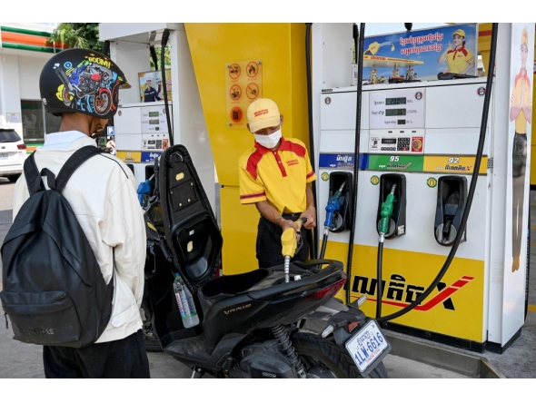 An employee pumps gasoline into the motorbike of a customer at a fuel station in Phnom Penh on April 1, 2026. (Photo by Tang Chhin Sothy / AFP)