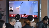 People watch a television screen showing a news broadcast with file footage of a North Korean missile test, at a train station in Seoul on April 8, 2026. (Photo by Jung Yeon-je / AFP)