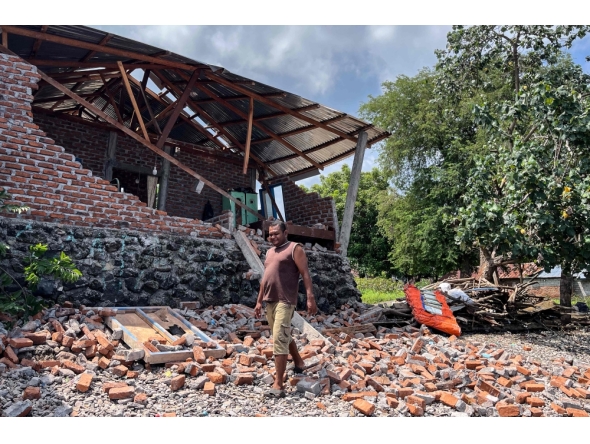 A resident clears debris from a damaged wall of his home after a shallow 4.9 magnitude earthquake in Adonara, East Nusa Tenggara on April 9, 2026, damaging dozens of homes and injuring multiple people, an official said. (Photo by Handrianus Hali / AFP)