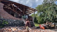 A resident clears debris from a damaged wall of his home after a shallow 4.9 magnitude earthquake in Adonara, East Nusa Tenggara on April 9, 2026, damaging dozens of homes and injuring multiple people, an official said. (Photo by Handrianus Hali / AFP)