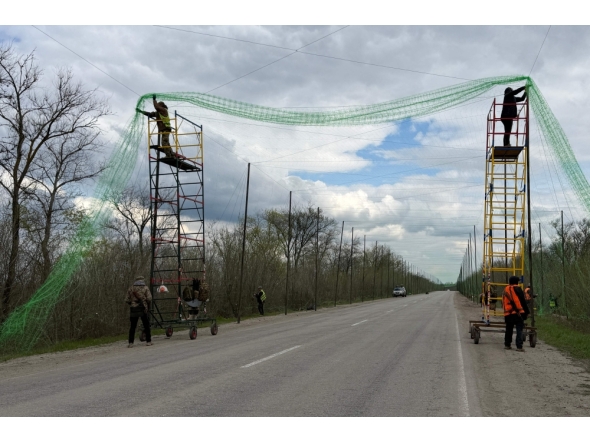 Ukrainian servicemen cover the road with a net to protect vehicles from drone attacks at an undisclosed location in the Zaporizhzhia region on April 10, 2026. (Photo by Darya Nazarova / AFP)